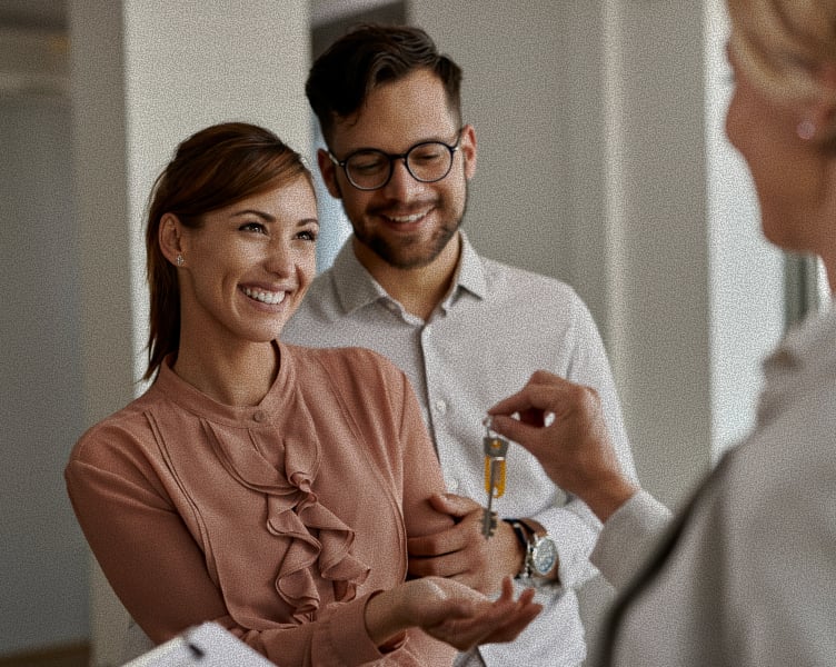 Real estate agent handing keys to a happy couple